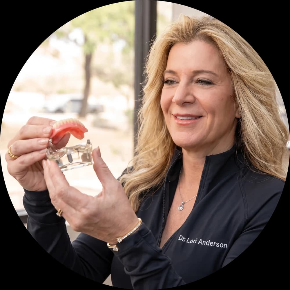 Dr. Lori Anderson holding a dental implant model